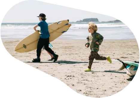 A man standing on the beach looking out on rock outcrops in the water